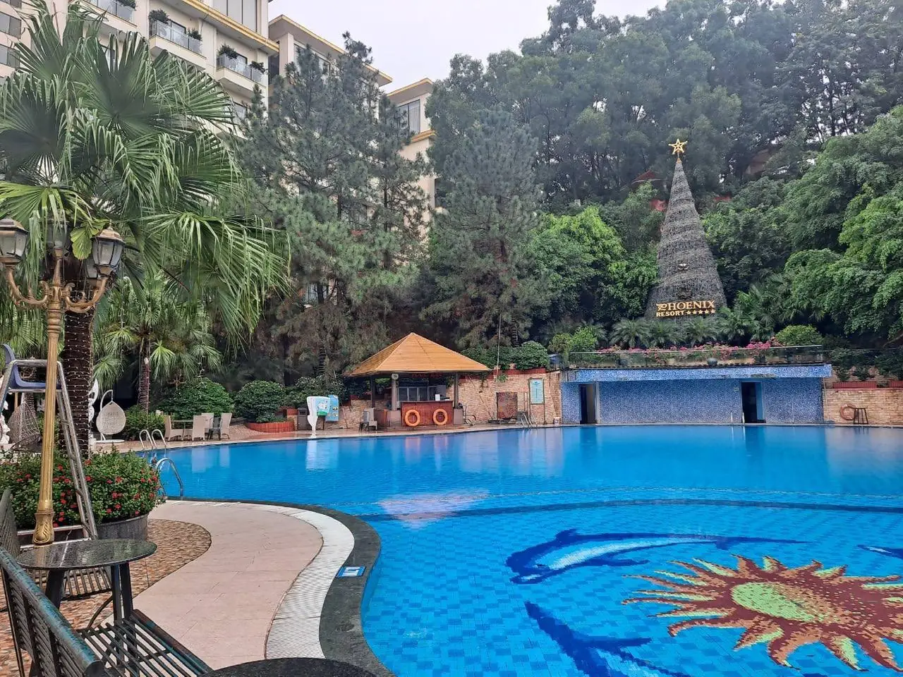 PHOENIX RESORT 표지와 녹지로 둘러싸인 야외 수영장
